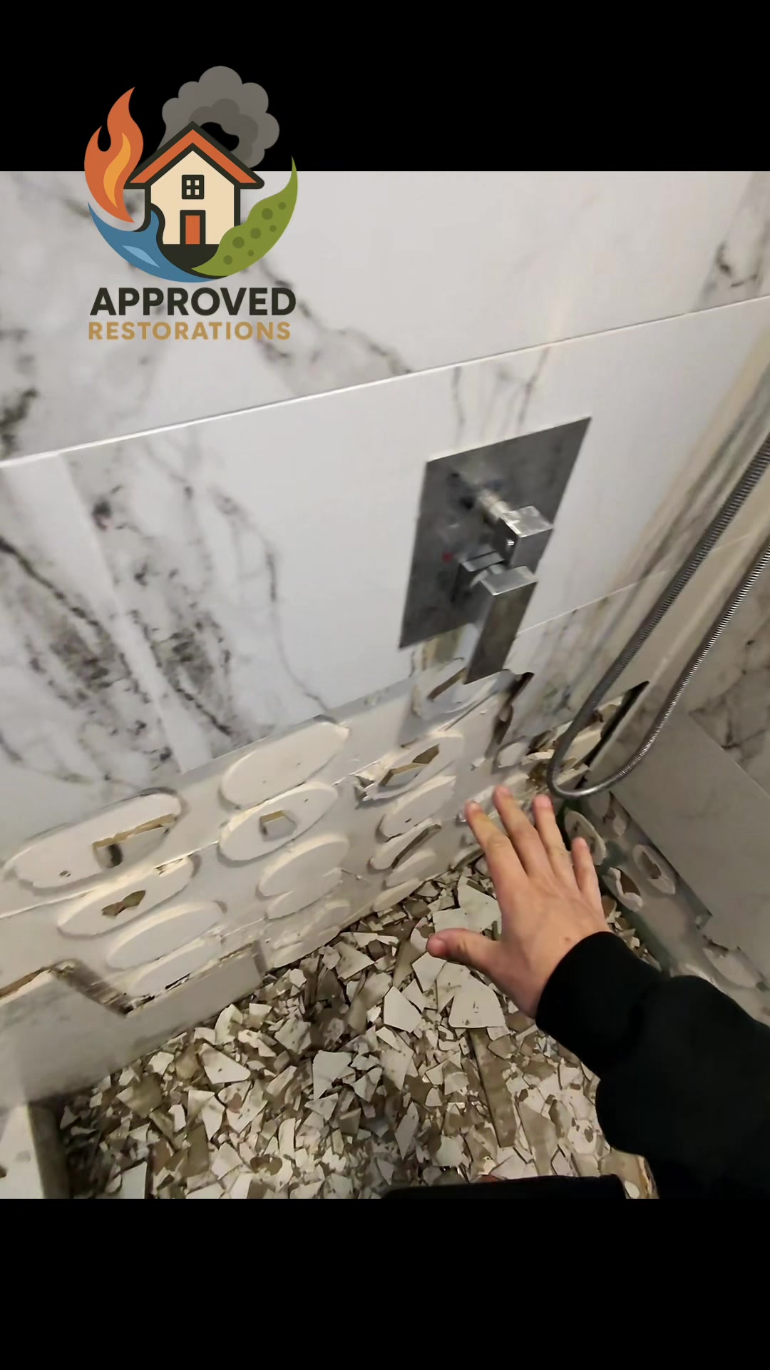 A persistent shower leak behind the valve compromised the entire wall cavity and wrecked the floor and ceiling below, so our crew is inspecting the failed adhesive behind these shattered marble tiles to track the exact moisture source before we haul out the saturated debris and prep the bathroom for a full rebuild.